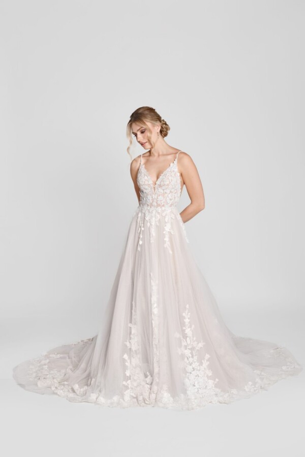 Charming bride to be wearing a spaghetti strap wedding dress with floral lace decals on the bodice and flowing onto the multilayered tulle skirt.