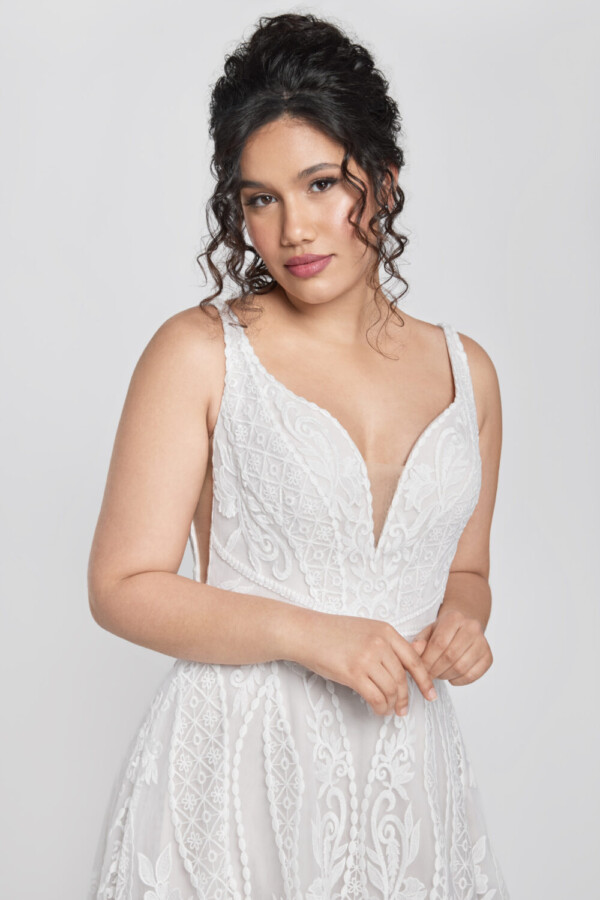 Bride to be wearing an art deco inspired lace wedding dress with chunky lace details and a deep v cut neckline.