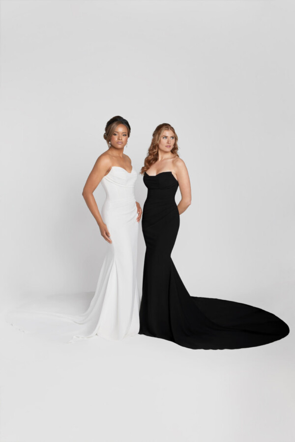 Two brides wearing the same sheath wedding dress with a sweetheart neckline and ruched bodice, one in black and one in white.