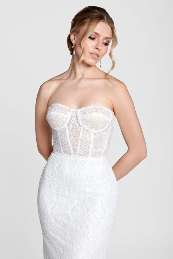 Shy bride to be wearing a lace, fit and flare wedding dress with a sweetheart neckline and corset bodice.