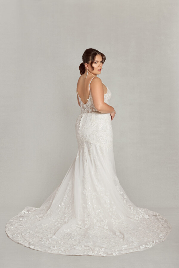 A boho style wedding dress worn by bride to be looking over her shoulder. The dress has floral detailing and buttons down the back.