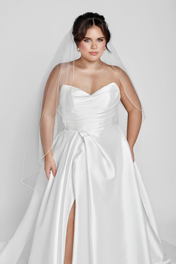 A timeless wedding dress style worn by a classic bride with a sweetheart neckline and basque waistline and slit up the thigh.