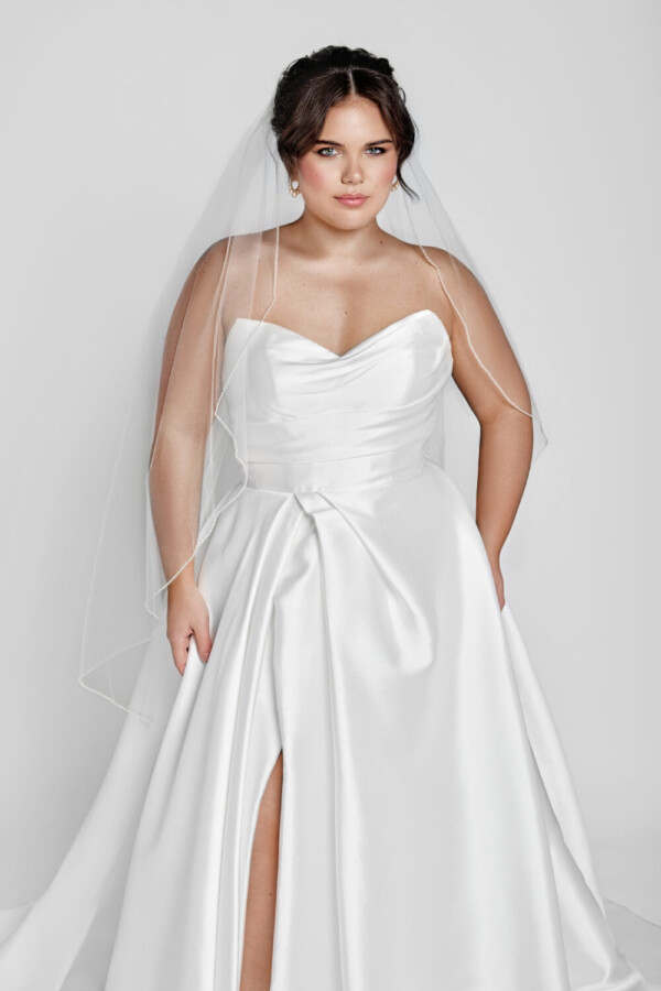 A timeless wedding dress style worn by a classic bride with a sweetheart neckline and basque waistline and slit up the thigh.