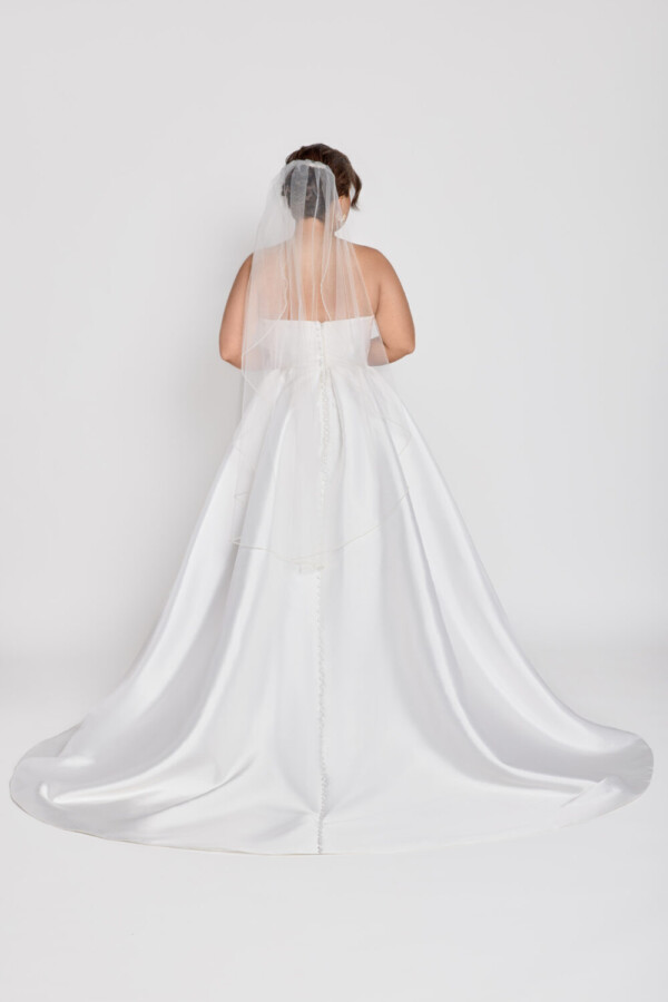 A timeless wedding dress style worn by a classic bride with a sweetheart neckline and basque waistline and slit up the thigh.