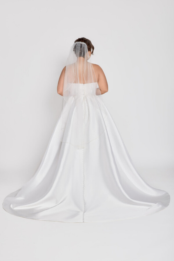 A timeless wedding dress style worn by a classic bride with a sweetheart neckline and basque waistline and slit up the thigh.