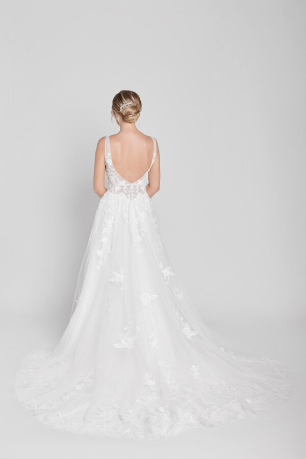 Bride to be wearing a floral lace wedding dress with a deep v cut neckline and multilayered tulle skirt with hidden pockets.