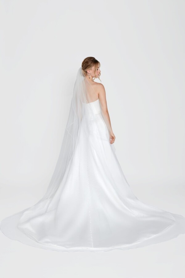 Simple wedding dress with a deep v cut neckline and simple, full skirt worn with a simple, long veil.