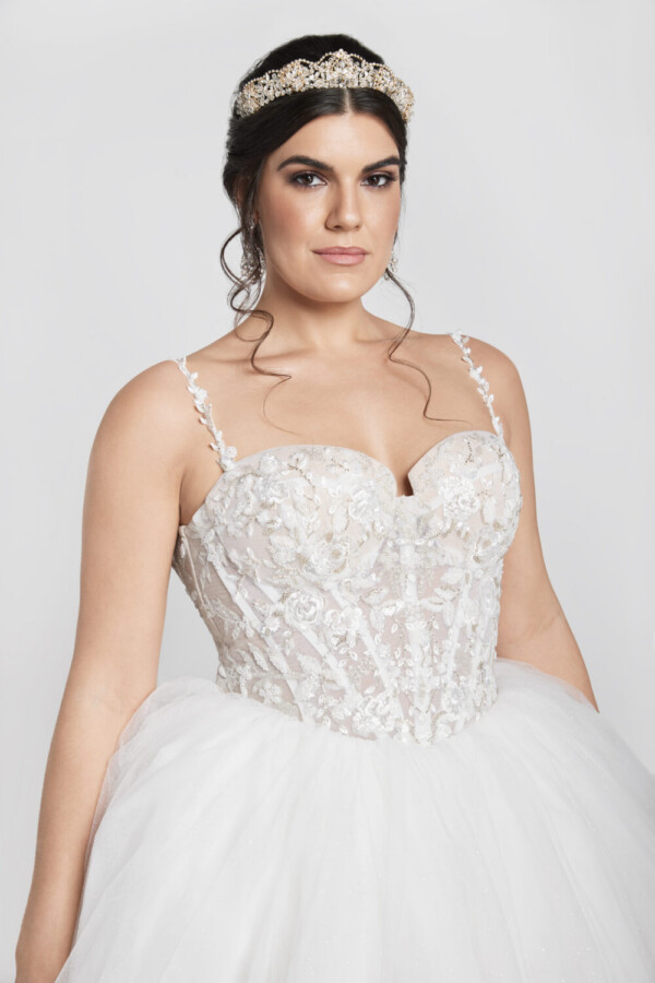 Charming bride to be wearing wedding dress with floral details on the corset bodice and a basque waistline into a multilayered tulle skirt.