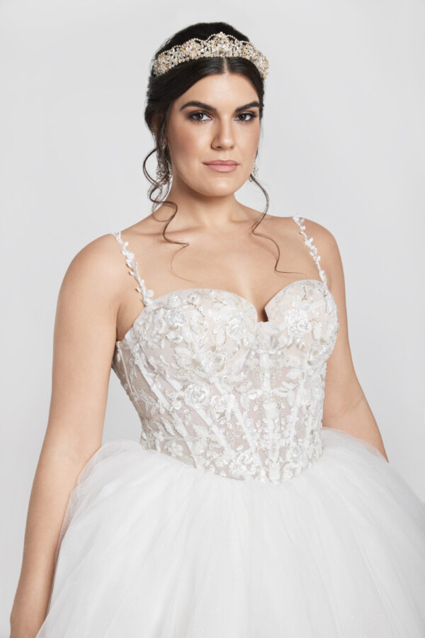 Charming bride to be wearing wedding dress with floral details on the corset bodice and a basque waistline into a multilayered tulle skirt.