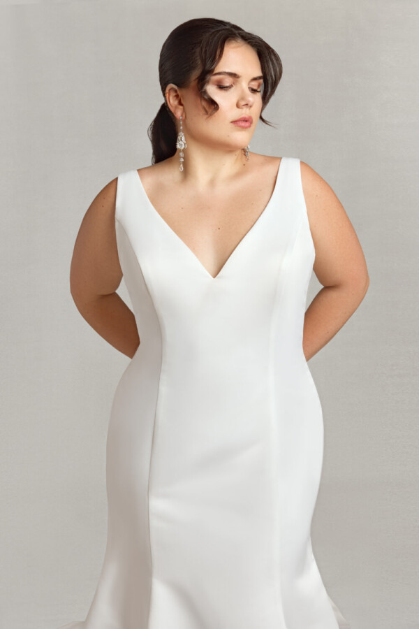 Stunning bride to be modeling a simple v cut wedding dress in a fit and flare shape.