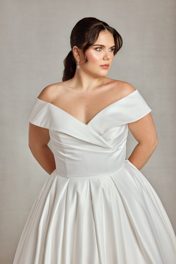 Traditional plus size bride modeling an off the shoulder sleeve wedding dress.
