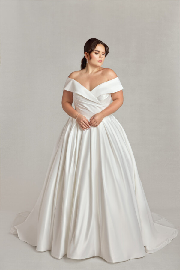 Traditional plus size bride modeling an off the shoulder sleeve wedding dress.