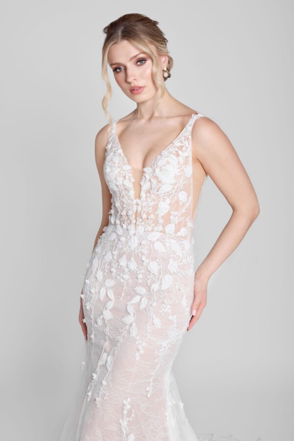 Bride wearing a fit and flare style wedding dress with deep v cut neckline and floral details flowing from the bodice onto the skirt.