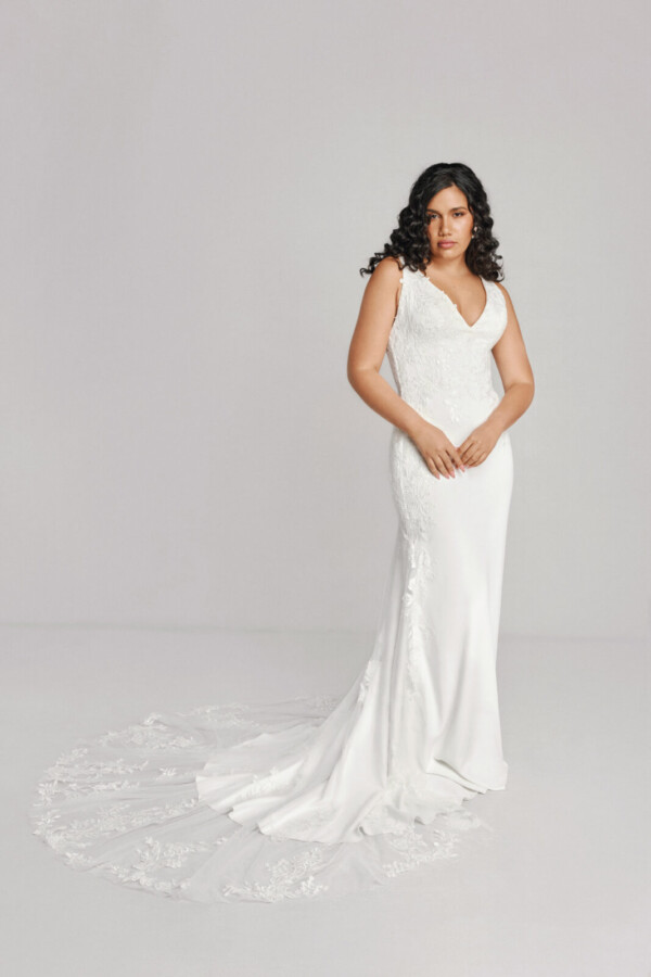 A bride in a white fitted lace floral deep v cut dress.