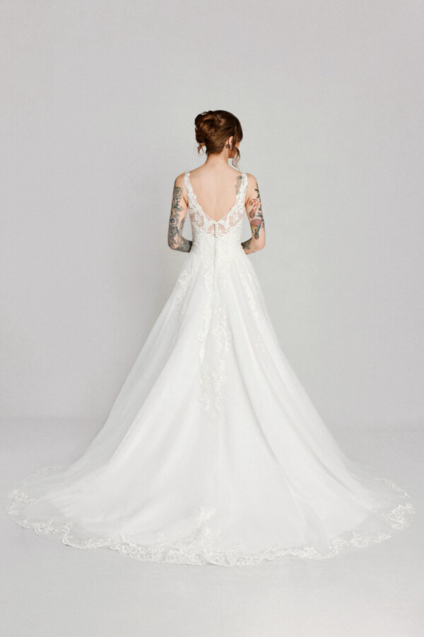 A bride in a white flowy lace floral open back dress.