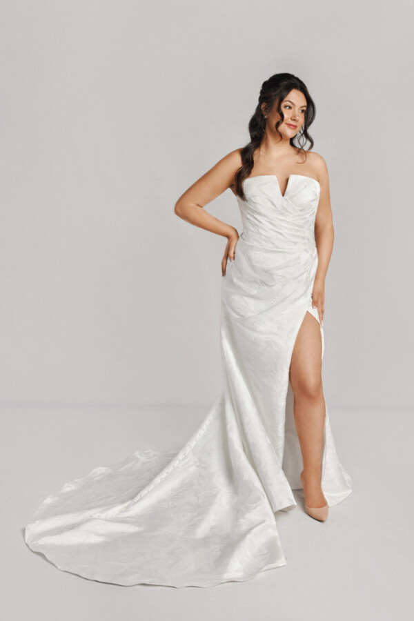 A bride in a white fitted slim strapless dress with a bow on the back.