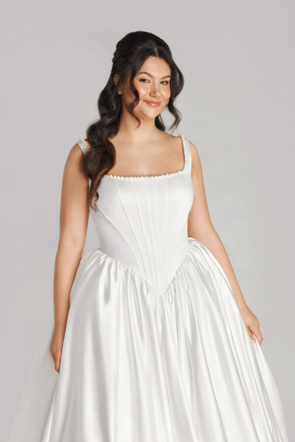 A bride in a white fitted and plated dress.