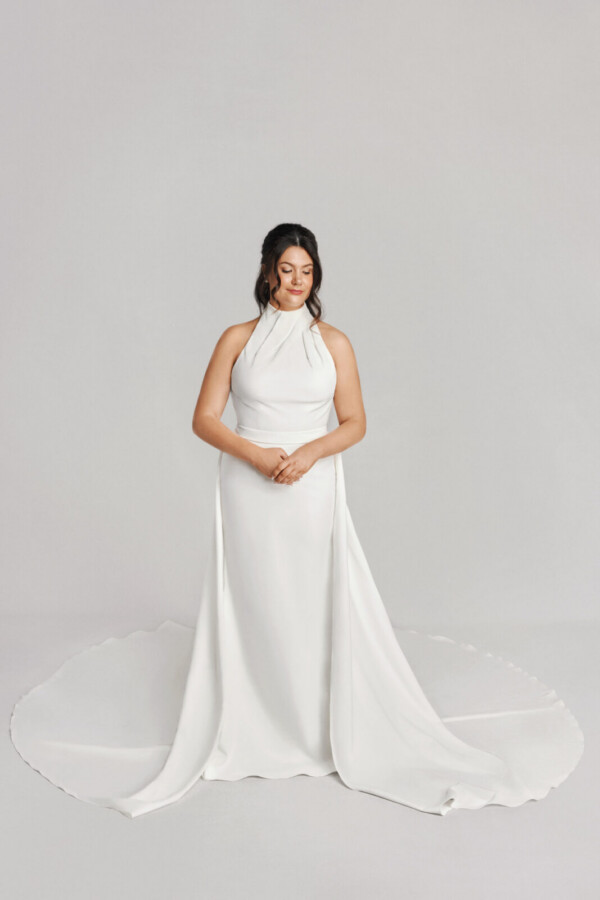 A bride in a white flowy floor length sleeveless dress.