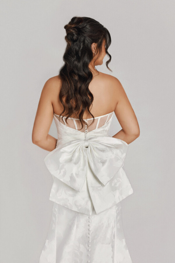 A bride in a white fitted slim strap dress with a bow on the back.
