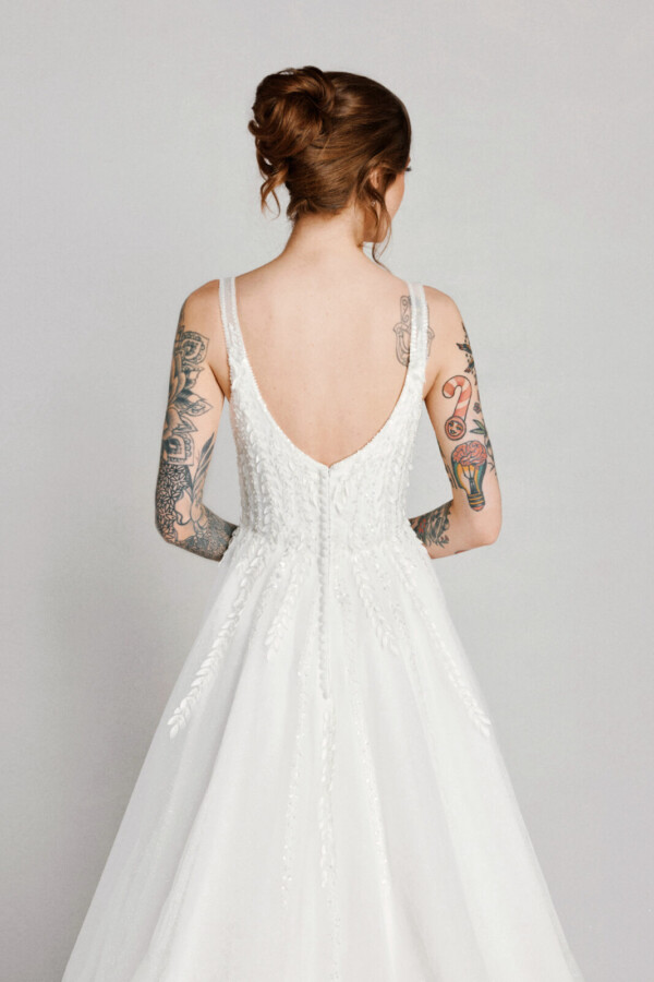 A bride in a white flowy lace floral open back dress.