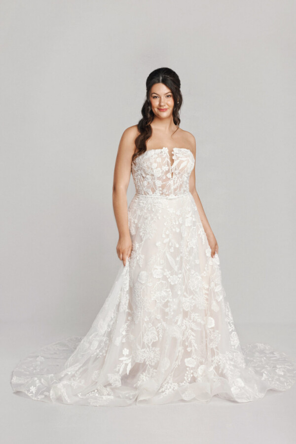 A bride in a white fitted floral strapless dress.