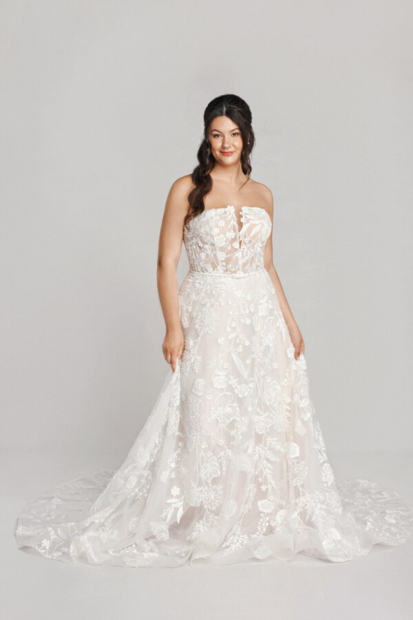 A bride in a white fitted floral strapless dress.