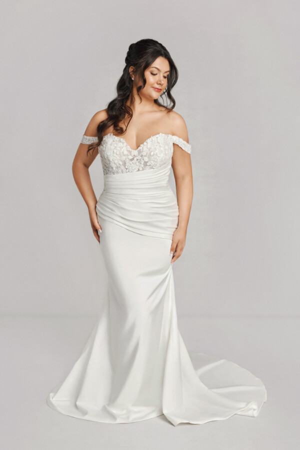 A bride in a white fitted off the shoulder floral dress.