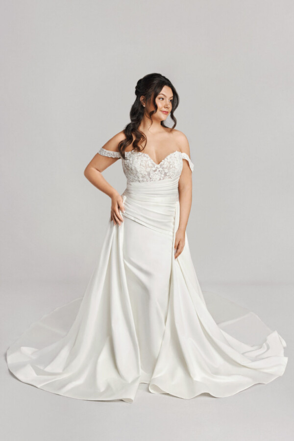 A bride in a white fitted off the shoulder floral dress.