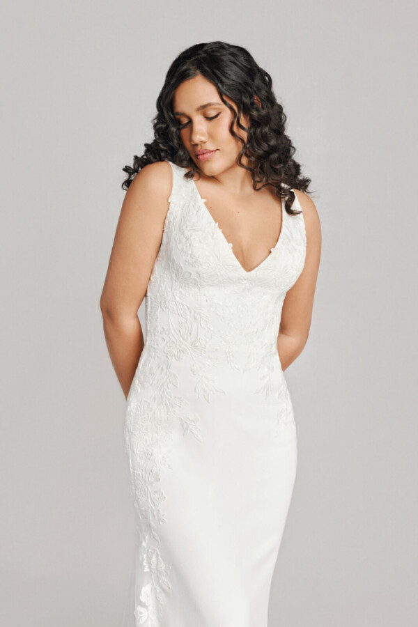 A bride in a white fitted lace floral deep v cut dress.