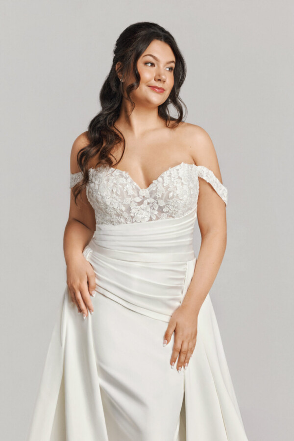 A bride in a white fitted off the shoulder floral dress.