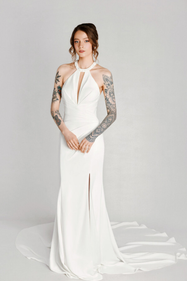 A bride with tattoos in a white flowy dress with leg slit.