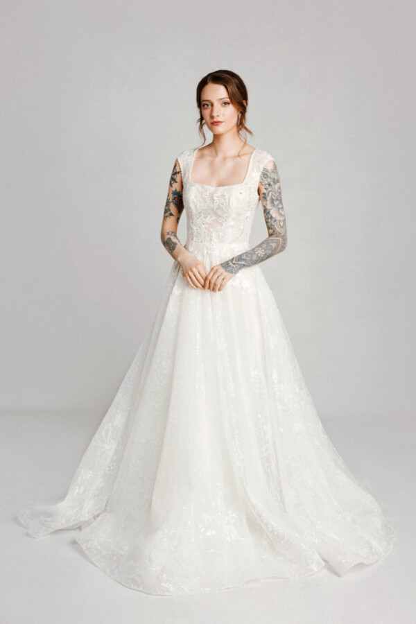 A bride with tattoos in a white fitted slim floral lace dress.
