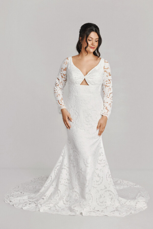 A bride in a white flowy lace floral deep v cut long sleeve dress.
