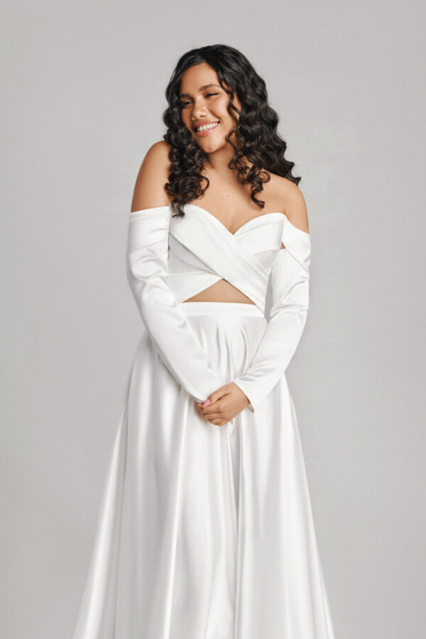 A bride in a white fitted off the shoulder flowy dress.