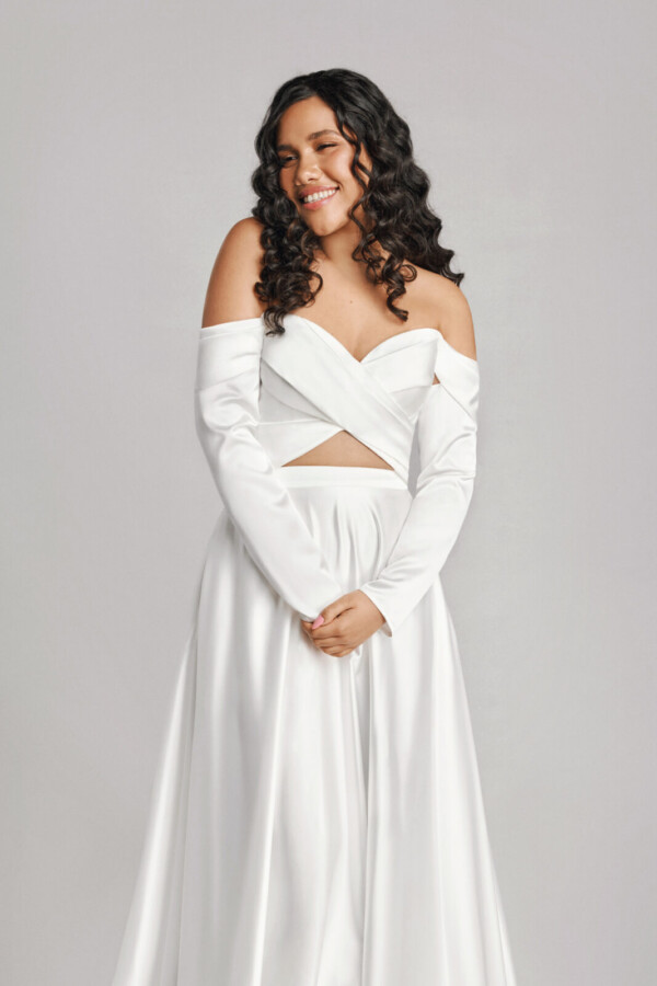 A bride in a white fitted off the shoulder flowy dress.