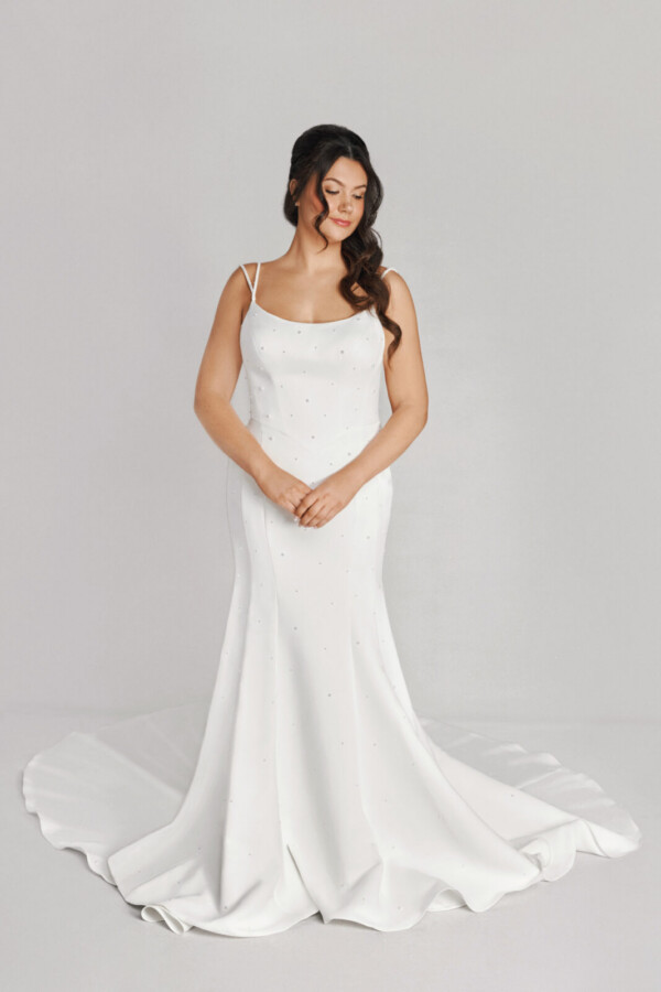 A bride in a white fitted slim strap dress with a bow on the back.