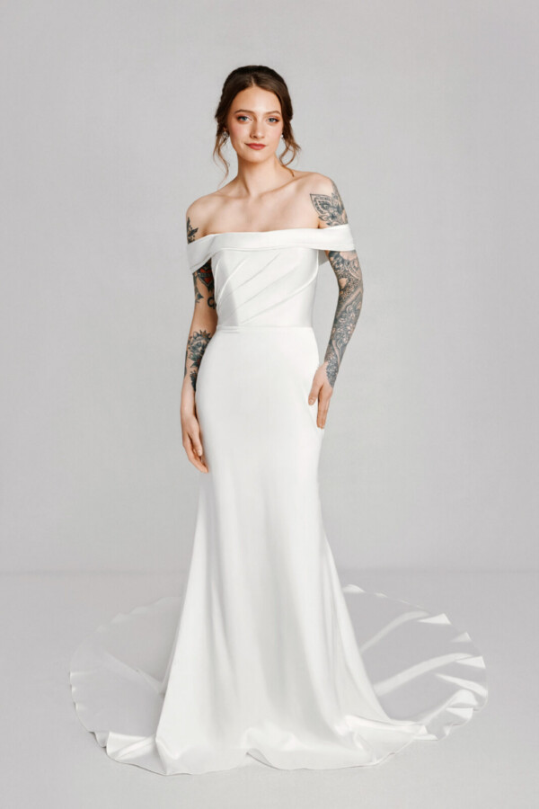 A bride with tattoos in a white fitted off the shoulder dress.