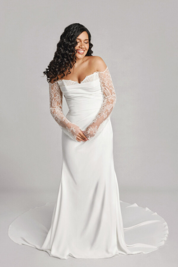 A bride in a white fitted strapless floral long sleeve lace dress.