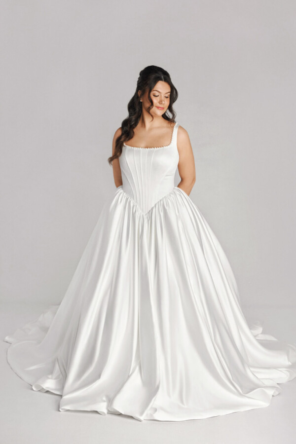 A bride in a white fitted and plated dress.