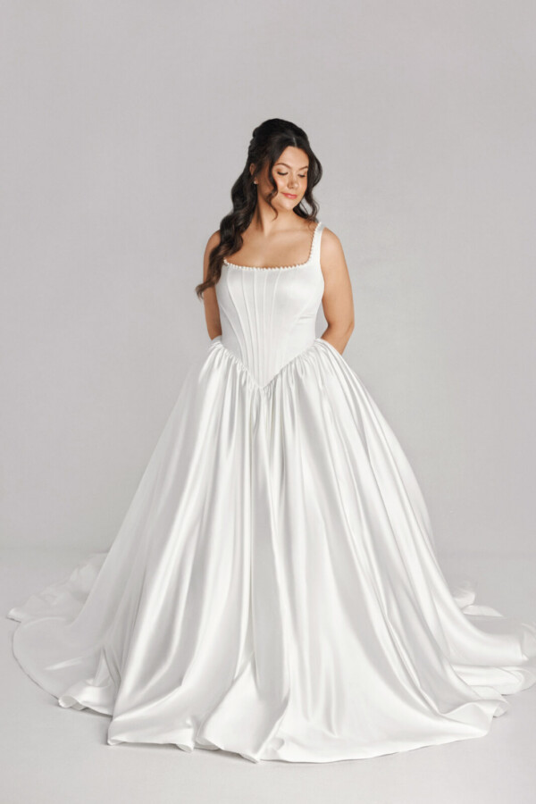 A bride in a white fitted and plated dress.