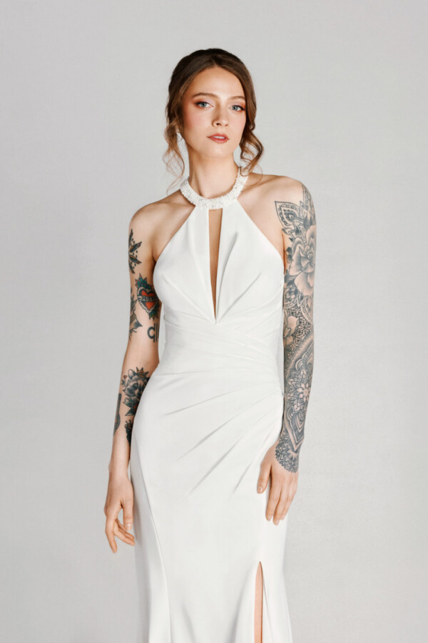 A bride with tattoos in a white flowy dress with leg slit.