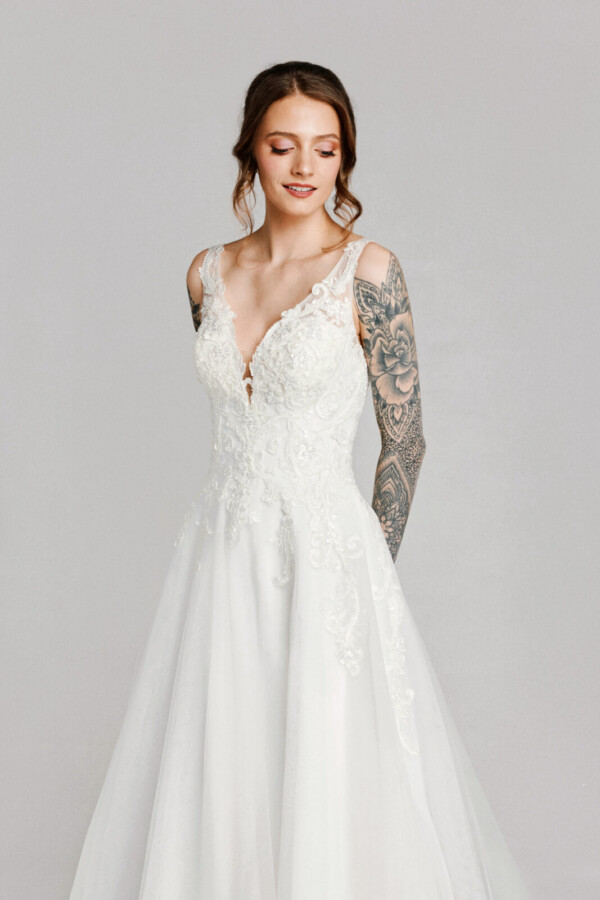 A bride in a white flowy lace floral deep v cut dress.