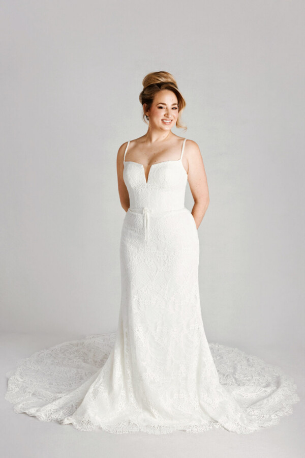 A bride in a white flowy lace floral deep v cut dress.