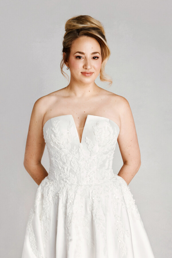 A bride in a white fitted deep v cut strapless floral lace dress.