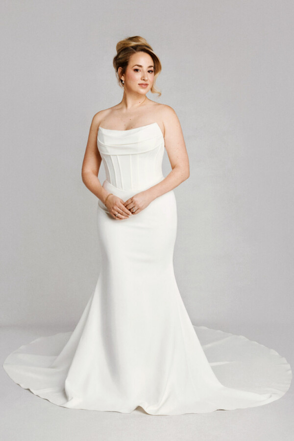 A bride in a white fitted strapless floor length dress.
