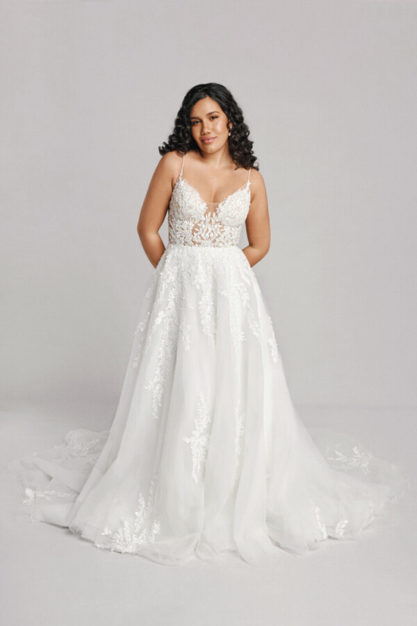 A bride in a white fitted slim strap floral lace dress.