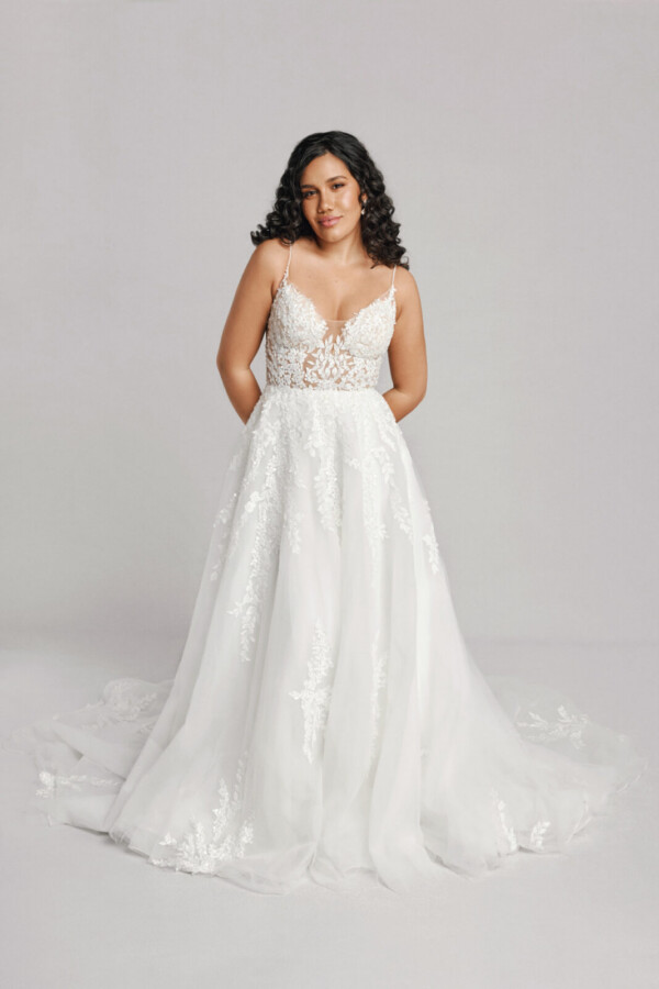 A bride in a white fitted slim strap floral lace dress.