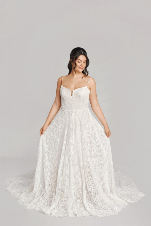 A bride in a white fitted slim strap floral lace dress.