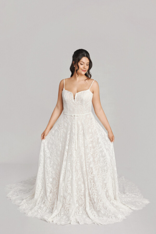 A bride in a white fitted slim strap floral lace dress.