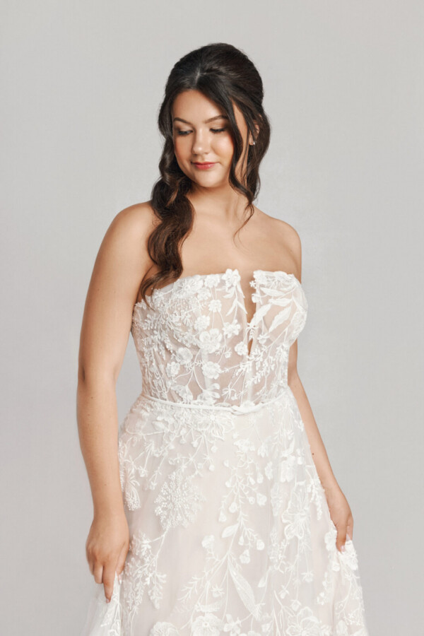 A bride in a white fitted floral strapless dress.